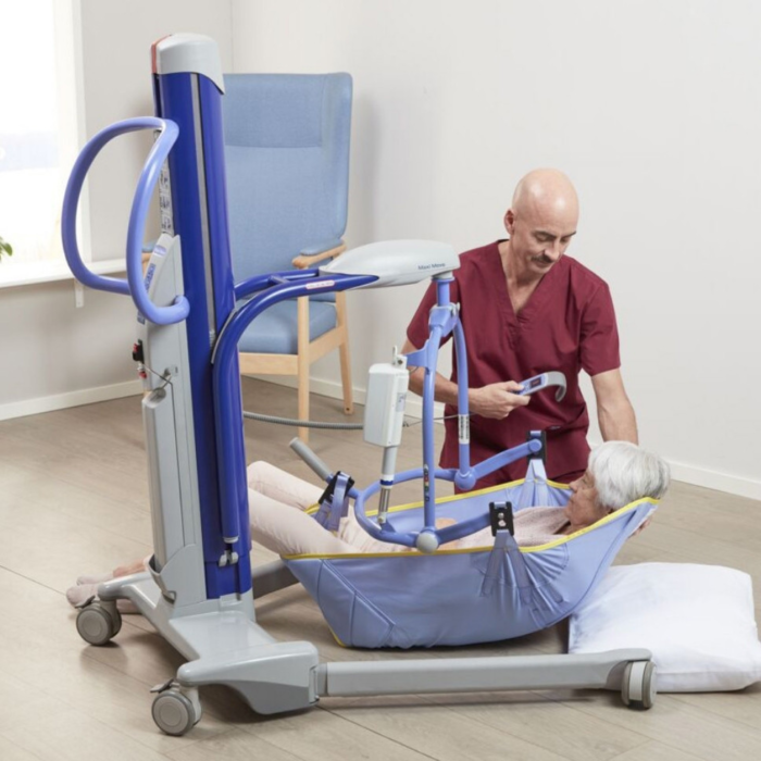 A patient being lifted by a nurse via a Maxi Move Floor Lift