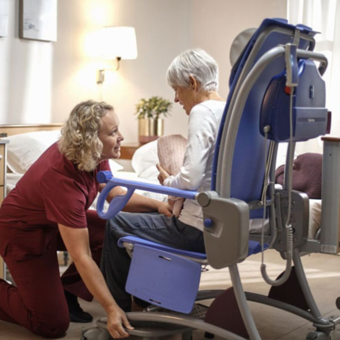 A patient on a Carino Shower and Hygiene Chair while a nurse helps her